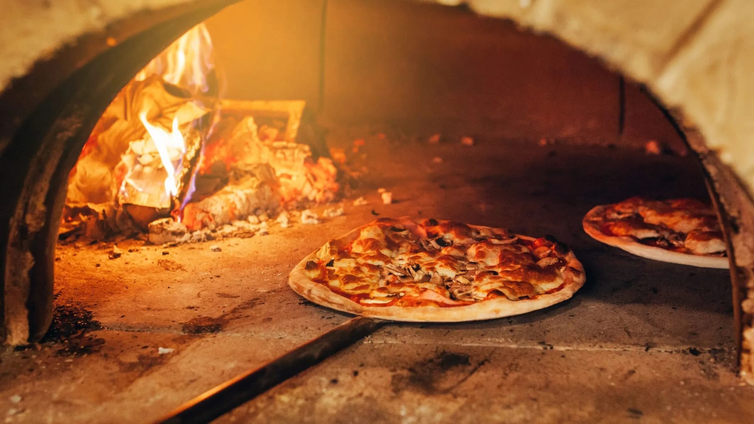 Two pizzas baking inside the brick oven at Romano's Family in Dover, Delaware